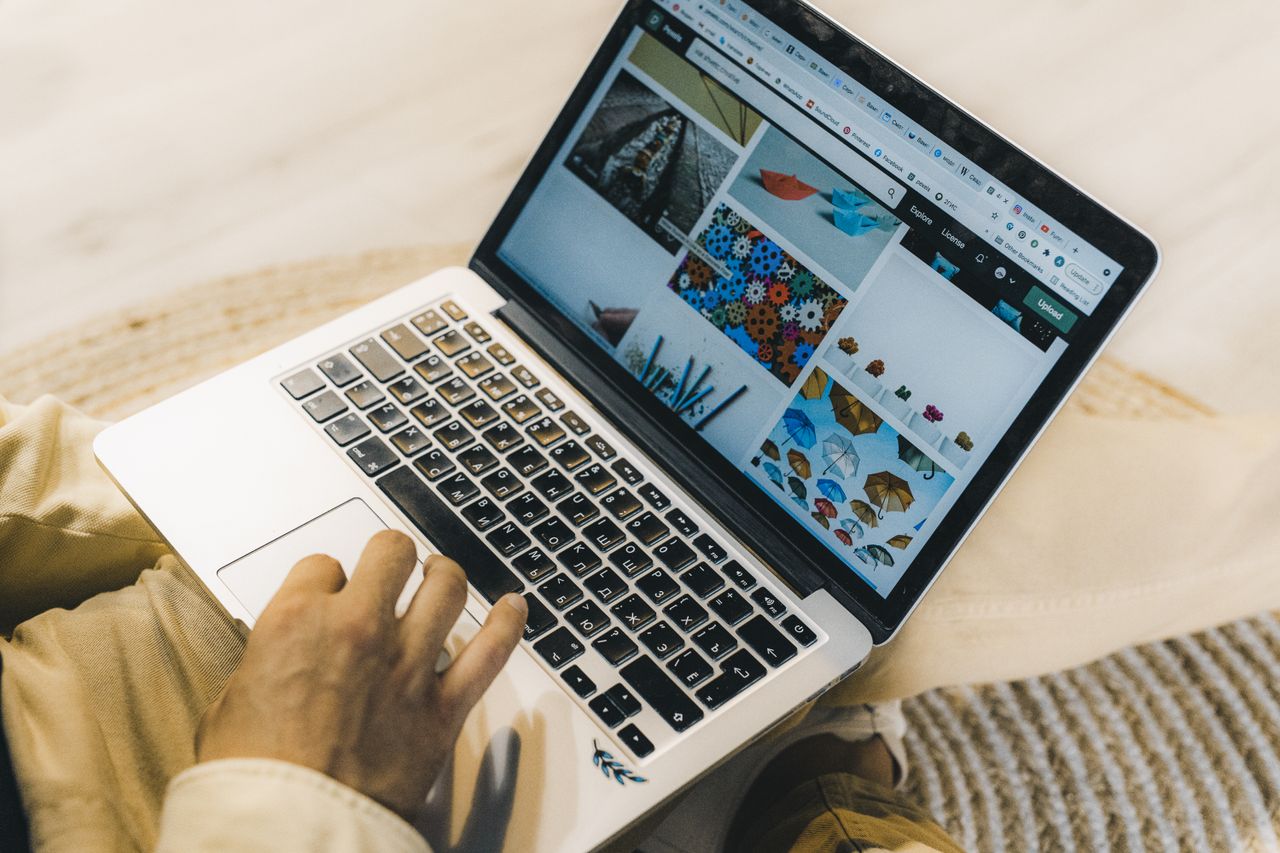 Une personne utilise un ordinateur portable pour consulter des sites de photos d’archive. Un travail de freelance dans un cadre chaleureux.
